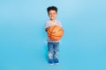 Full length body size view of nice cheerful boy playing basketball isolated over bright blue color background Royalty Free Stock Photo