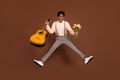 Full length body size view of nice cheerful funky guy jumping holding guitar tulips sale isolated over brown color Royalty Free Stock Photo