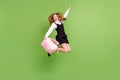 Full length body size view of pretty cheerful carefree girl jumping carrying bag over green color background