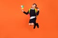 Full length body size view of pretty funny preteen girl jumping playing paper fan pout lips isolated over bright orange Royalty Free Stock Photo