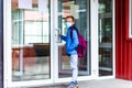 Full length boy wearing protective mask is trying to open the school door. Behind the backpack Schoolboy look at camera Royalty Free Stock Photo