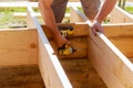 Full length carpenter drilling wood at construction site