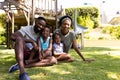 Full length of cheerful african american parents and children sitting on grassy field in park Royalty Free Stock Photo