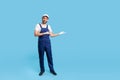 Full length cheerful workman in blue overalls, cap and protective gloves standing, showing empty space Royalty Free Stock Photo