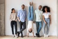 Full length cheery friends laughing photographing posing near wall indoors