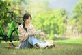 Full length of concentrated Asian female student reading book on campus lawn next to her bicycle Royalty Free Stock Photo