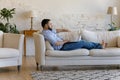 Concentrated young man using computer lying on couch. Royalty Free Stock Photo