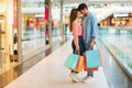 Full Length Of Couple Doing Shopping Hugging Standing In Mall