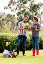 Full length of couple holding potted plants at lawn