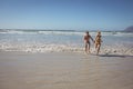 Full length of couple running on shore at beach Royalty Free Stock Photo