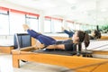 Determined Woman Pulling Resistance Bands On Pilates Reformer