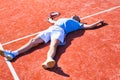 Full length of disappointed mature man lying by tennis racket on court during summer Royalty Free Stock Photo