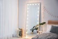 Full length dressing mirror with lamps in stylish bedroom interior