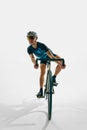Full-length dynamic image of young man, professional cyclist in motion, training isolated on white background. Royalty Free Stock Photo