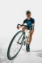 Full-length dynamic image of young man, professional cyclist in motion, training isolated on white background. Royalty Free Stock Photo