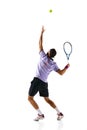 Full-length dynamic image of young man, tennis player in motion, serving ball with racket isolated over white background Royalty Free Stock Photo