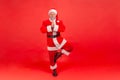 Full length elderly gray bearded santa claus meditating standing in tree pose and pressing hands, relaxing and resting before