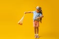 full length of excited kid in straw hat pointing with finger at reusable string bag with oranges on yellow. Royalty Free Stock Photo