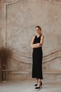Full-length fashion portrait of a young model woman with perfect slim body wearing a black evening dress posing in a Royalty Free Stock Photo