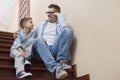 Full length of father and son looking at each other while sitting on steps at home Royalty Free Stock Photo