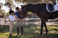 Full length of female jockey with sister feeding horse Royalty Free Stock Photo