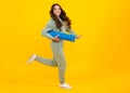 Full length of a fitness teen girl in sportswear hold yoga mat posing over yellow background. Fitness model child Royalty Free Stock Photo