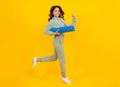 Full length of a fitness teen girl in sportswear hold yoga mat posing over yellow background. Run and jump. Fitness Royalty Free Stock Photo