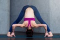 Full-length front view of sporty young woman practicing yoga doing standing straddle forward bend pose, Prasarita