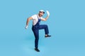 Full length funny happy handyman in blue uniform striding in big step, smiling crazy comical and hurrying to client