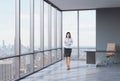 Full length of the girl with crossed hands is standing in the corner panoramic office. Royalty Free Stock Photo