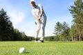 Full length of golf player playing golf on sunny day. Professional male golfer taking shot on golf course