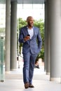 Full length handsome african businessman walking with mobile phone Royalty Free Stock Photo