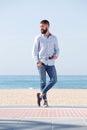 Full length handsome man holding sunglasses and standing on beach Royalty Free Stock Photo