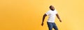 Full length of handsome young black man jumping against yellow background. Royalty Free Stock Photo