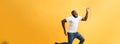 Full length of handsome young black man jumping against yellow background. Royalty Free Stock Photo