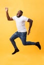 Full length of handsome young black man jumping against yellow background. Royalty Free Stock Photo