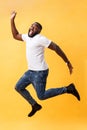 Full length of handsome young black man jumping against yellow background. Royalty Free Stock Photo