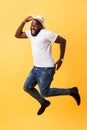 Full length of handsome young black man jumping against yellow background. Royalty Free Stock Photo