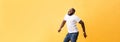 Full length of handsome young black man jumping against yellow background. Royalty Free Stock Photo