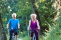 Happy and active senior couple riding bicycles outdoors in the park