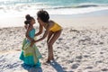 Full length of happy african american mother and daughter enjoying sunny day at beach Royalty Free Stock Photo