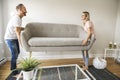 Full length of happy couple placing sofa in living room of new home Royalty Free Stock Photo