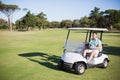 Full length of happy golfer man driving golf buggy