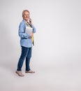 Full length of happy senior businesswoman with tablet discussing over phone call on white background Royalty Free Stock Photo