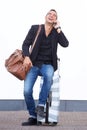 Full length happy travel man sitting on suitcase by white wall and talking with mobile phone Royalty Free Stock Photo