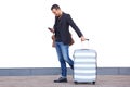 Full length happy travel man walking by white wall with suitcase bag and mobile phone Royalty Free Stock Photo