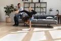 Happy young African American father watching little daughter doing acrobatics.