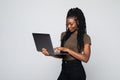 Full length of a happy young african woman working on laptop computer standing isolated over gray background Royalty Free Stock Photo