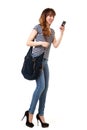 Full length happy young woman walking with mobile phone and purse against isolated white background Royalty Free Stock Photo