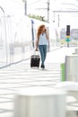 Full length happy young woman walking at train station with mobile phone and bag Royalty Free Stock Photo